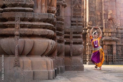 Indian classical dancer in traditional dress and posing in front of temple. Classical indian temple dance form Odissi. Dance pose photo