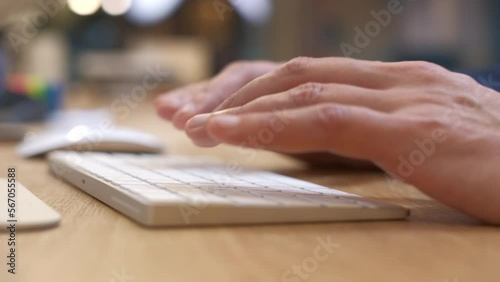 Men's hands type on a white keyboard, then scroll with the mouse. The manager in a business suit. Soft keystrokes. Gadgets with modern design. Office interior with a bright desk. Close-up, side view.