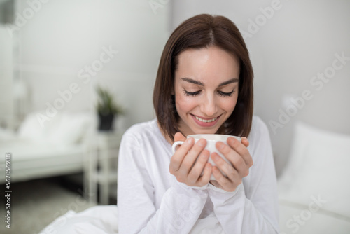 Closeup of young lady enjoying fresh morning coffee at home