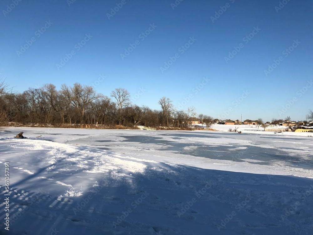 Snow-covered ground with the pond frozen in winter Snow-covered ground with the pond frozen in winter