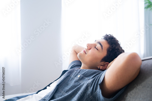 Hispanic boy relaxing lying on couch with closed eyes. Teenager dreaming and planning future.