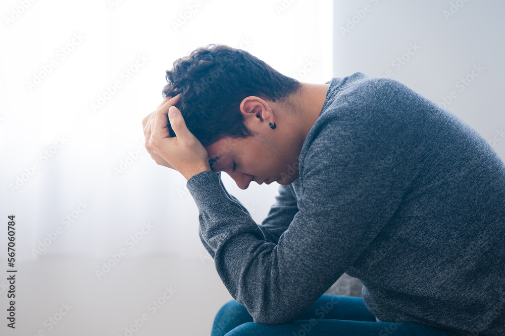 Sad hispanic teenager boy sitting hands on head. Depression, anxiety, stress and mental health concept - obrazy, fototapety, plakaty 