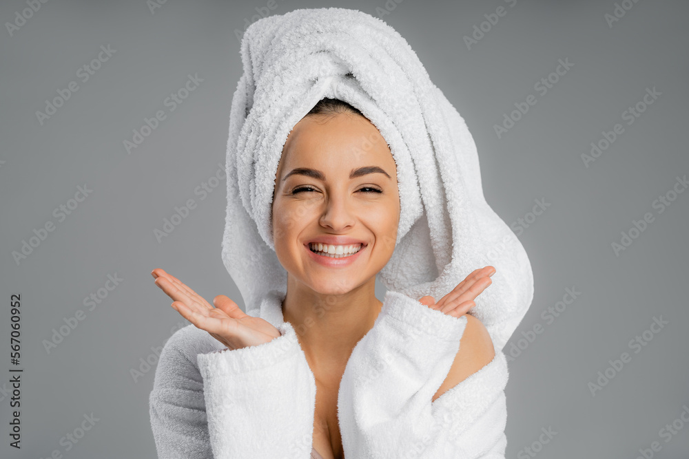 Obraz premium Positive young woman with towel on head looking at camera isolated on grey.