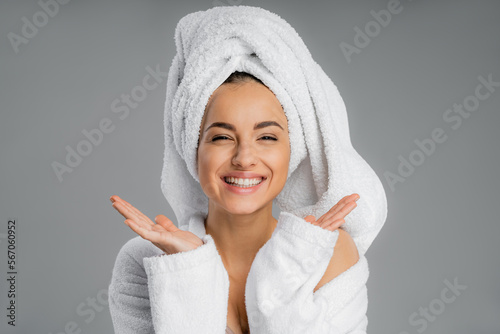 Positive young woman with towel on head looking at camera isolated on grey.