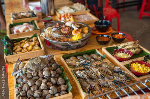 Wood Table with deliciouse seafood, shrimp, crab, mussle, pork saussage and vegetable in bbq grill restaurant from thailand