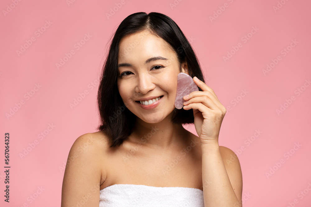 Portrait of smiling beautiful naked asian woman using facial gua sha jade board Portrait of smiling beautiful naked asian woman using facial gua sha jade board