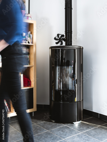 Woman walking near pellet stove in living room with library