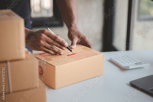 A person writing a customer's shipping address, an online store owner verifying an order before sending it to a customer, selling products online on websites and selling platforms.