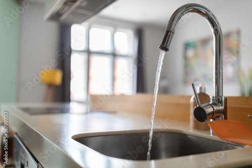 Close up shot of modern kitchen faucet with water running from tap