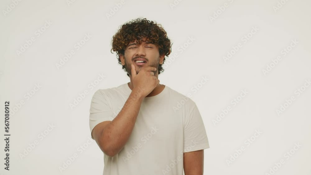 Confused brunette man posing in studio. Front view of bewildered guy rubbing his beard isolated on white background Confused brunette man posing in studio. Front view of bewildered guy rubbing his beard isolated on white background