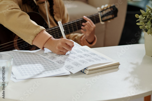 Fotografi Closeup image of girl practicing exercise for her acoustic guitar class