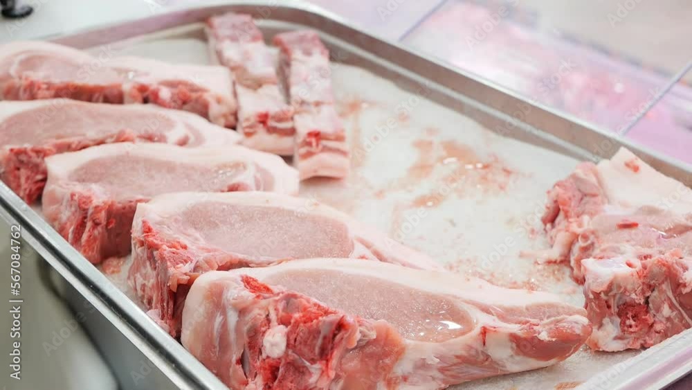 The hands of the butcher take pieces of cut fresh meat lying on a tray with a polystyrene bedding. retail trade in meat products in grocery stores of large supermarkets. Food industry. The hands of the butcher take pieces of cut fresh meat lying on a tray with a polystyrene bedding. retail trade in meat products in grocery stores of large supermarkets. Food industry.