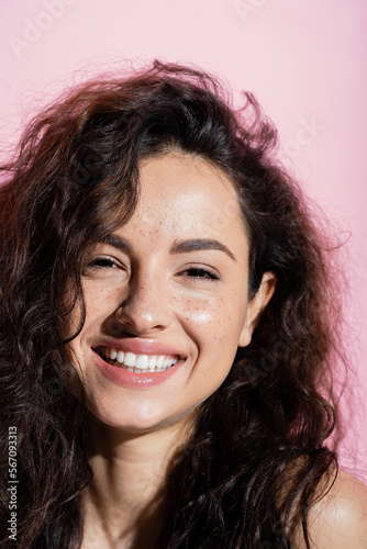 Young freckled woman smiling at camera isolated on pink.