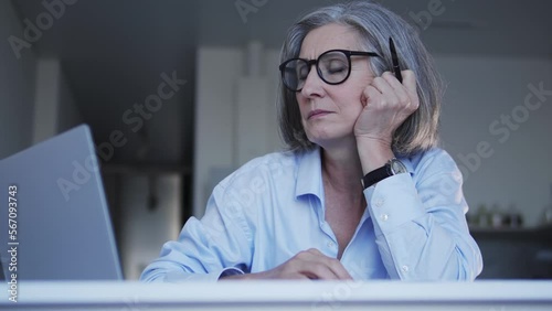 Tired overworked woman in big eyeglasses falling asleep looking at laptop display, female market research analyst working with dull datas, feeling herself exhausted