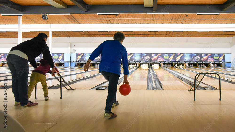 Older woman and father with child bowling together at bowling alley