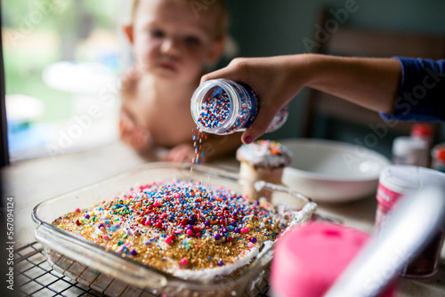 Girl decorating cake with overabundance of sprinkles photo