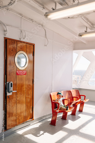 A little boy sits in a chair on a ferry in Washington State. photo