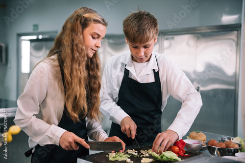 Two student boy and girl enjoy studying cooking class at school kitchen.