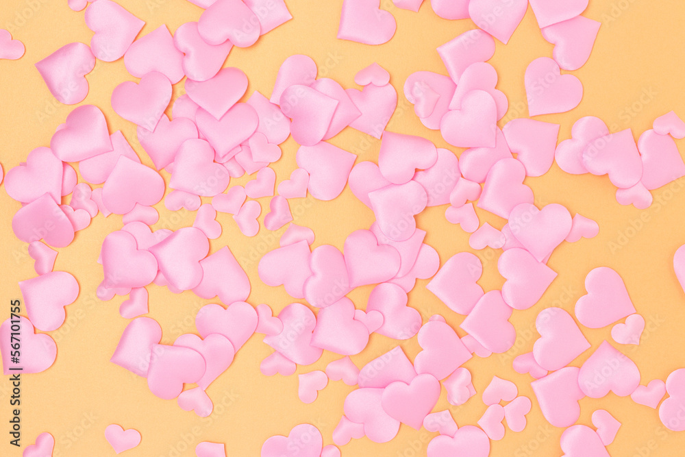 Texture made of textile pink confetti in a heart shape on a gold colored background. Holidays creative composition.