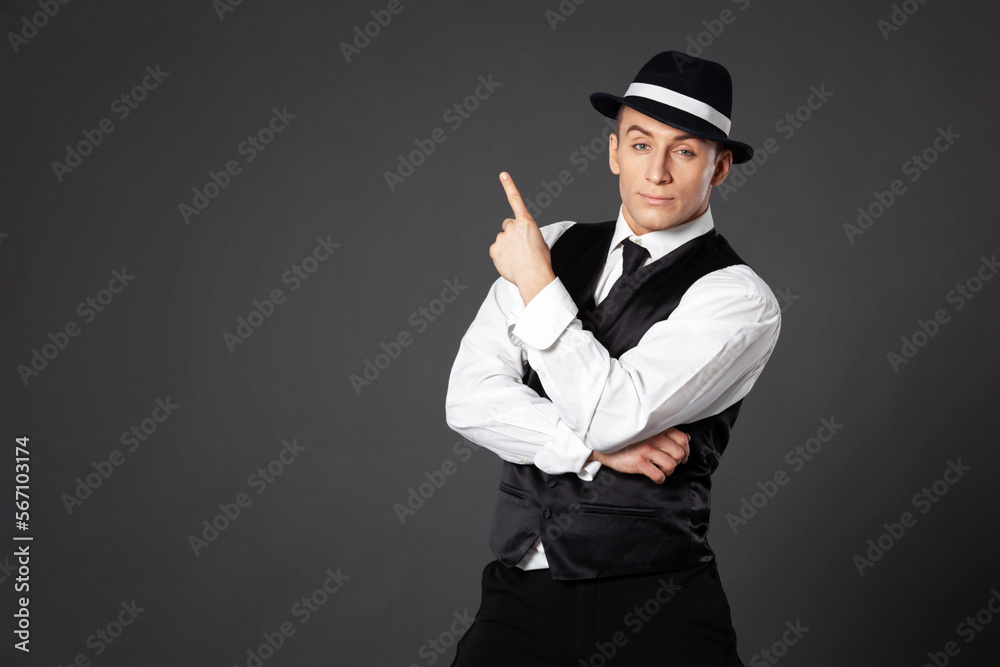 Confident young man posing in gangster style suite.