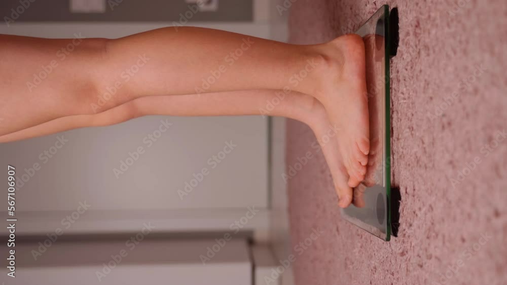 Girl stand on the scales and then gets off them in room close up. Young female person measuring mass of the body. Barefoot, pink carpet visible. Healthy lifestyle and self care from youth age concept Girl stand on the scales and then gets off them in room close up. Young female person measuring mass of the body. Barefoot, pink carpet visible. Healthy lifestyle and self care from youth age concept