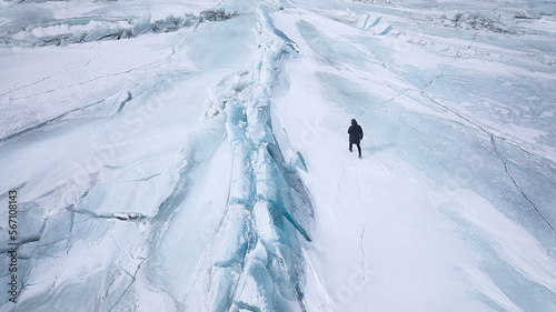 A man walks on cracked blue ice in the Arctic to the north of blue ice blocks