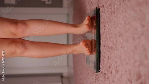 Girls legs on the scales close-up. She moving toes fun. Young female person measure body weight mass on transparent glass scales. Caucasian child is barefoot. Normal weight and healthy lifestyle