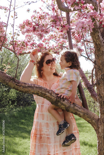 Woman holding child on a tree branch in Spring
