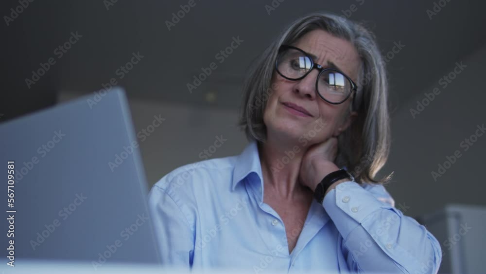 Gray-haired woman feeling pain in neck doing her work on laptop, healthcare