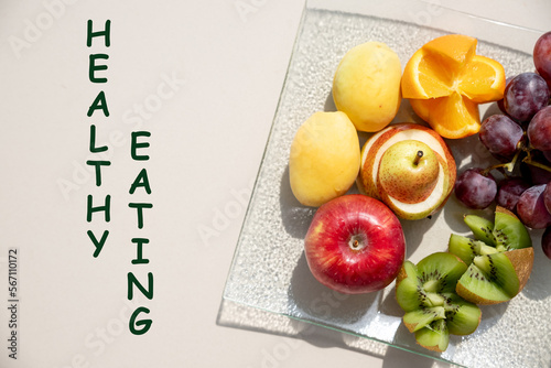 Assortment of fresh organic fruit on white table with text healthy eating. Healthy food concept.fresh summer salad of various fruits.Vitamins natural nutrition concept