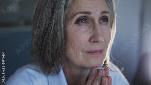Happy mature woman opening her heart and soul to God folding hands in pray