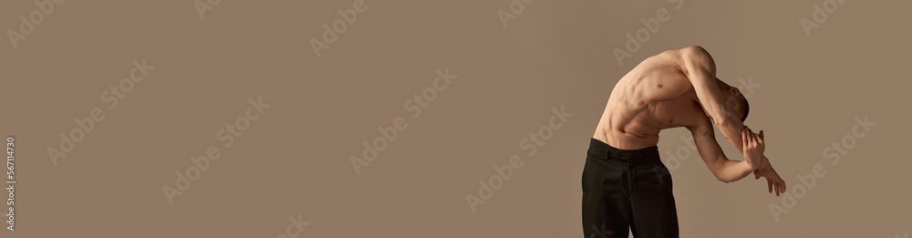 Fototapeta premium Portrait of handsome young redhead man posing shirtless in pants on grey studio background. Muscular body shape. Concept of men's health and beauty, body care, fitness. Banner. Copy space for ad, text