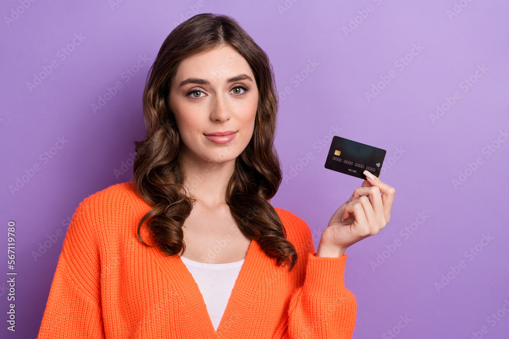 Photo of young confident banker wear orange stylish cardigan hold black premium debit card shopping choice isolated on violet color background Photo of young confident banker wear orange stylish cardigan hold black premium debit card shopping choice isolated on violet color background