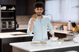 Young Hispanic man baking homemade cookies while smiling at the camera - Young man preparing cookies - Pastry man