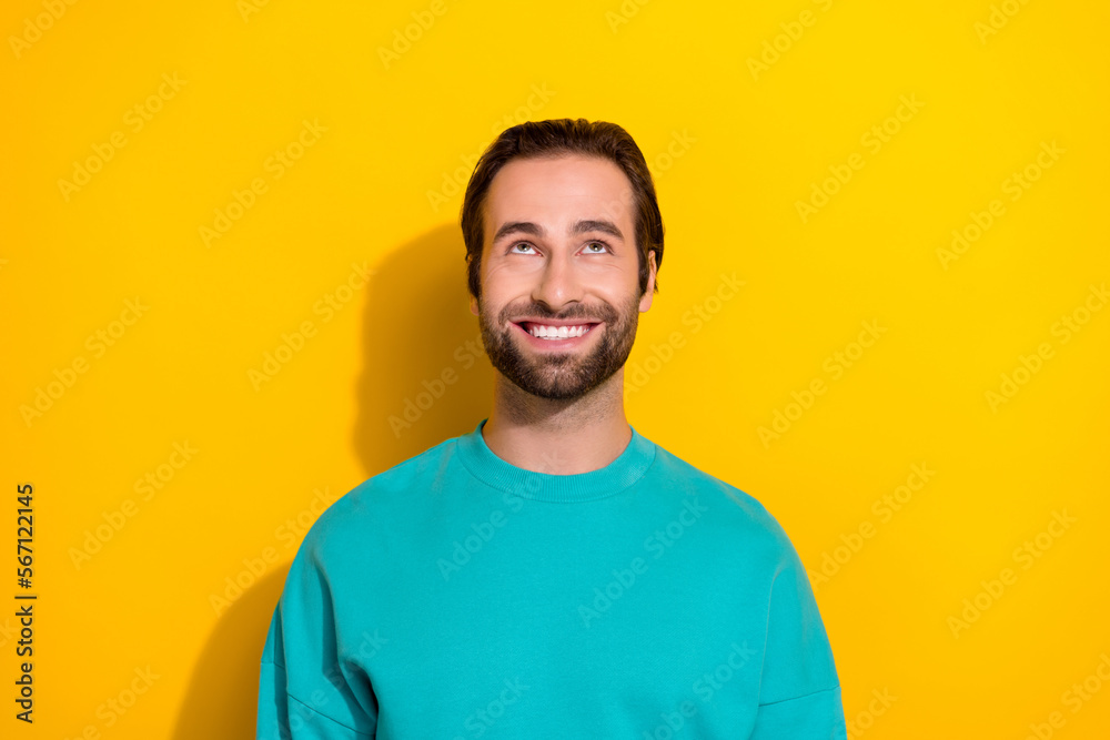 Photo of young cheerful good mood smile brunet hair stubble guy wear blue sweater smile look up cheap prices isolated on yellow color background Photo of young cheerful good mood smile brunet hair stubble guy wear blue sweater smile look up cheap prices isolated on yellow color background