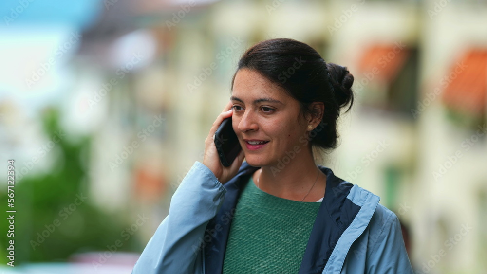 Smiling woman speaking on phone outside. Portrait of person talking with cellphone standing in city Smiling woman speaking on phone outside. Portrait of person talking with cellphone standing in city