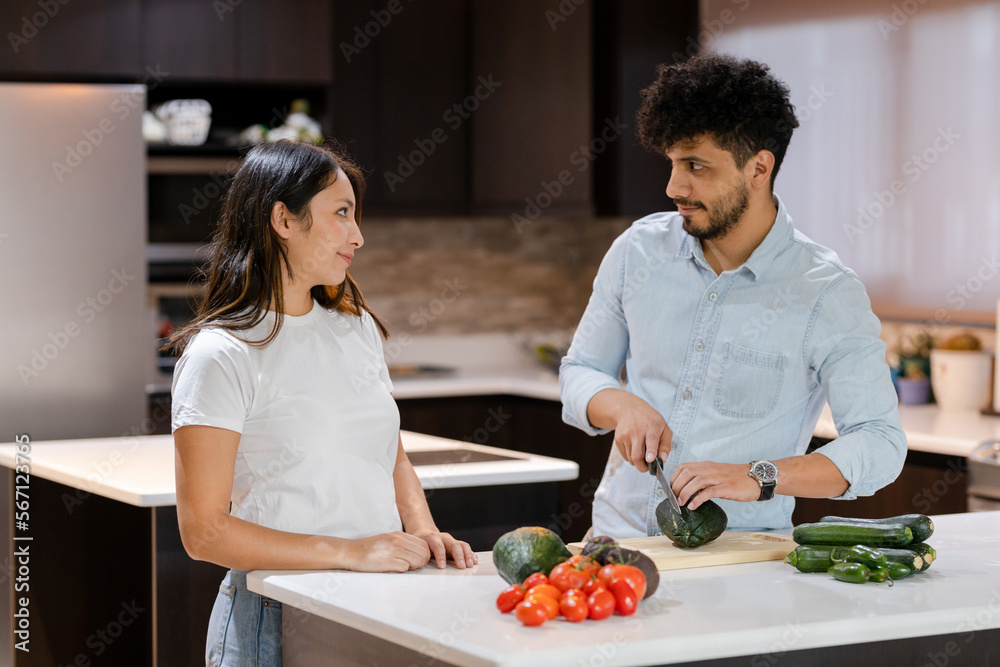 Hispanic couple cooking healthy salad in their kitchen - Young man making healthy recipes together with his partner - Young couple in their kitchen