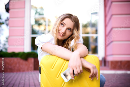 happy woman moving to new home, holding yellow suitcase. woman enjoy changes in life