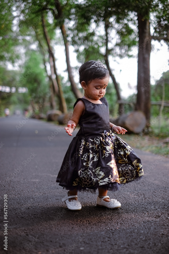 South asian cute little adorable baby girl walking on a rural road wearing colourful princess dress South asian cute little adorable baby girl walking on a rural road wearing colourful princess dress