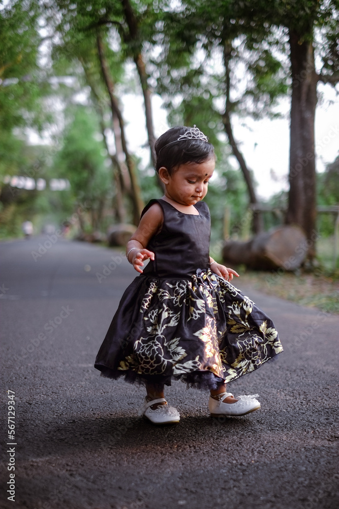 South asian cute little adorable baby girl walking on a rural road wearing colourful princess dress South asian cute little adorable baby girl walking on a rural road wearing colourful princess dress