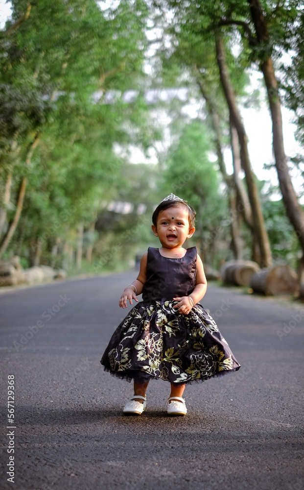 South asian cute little adorable baby girl walking on a rural road wearing colourful princess dress South asian cute little adorable baby girl walking on a rural road wearing colourful princess dress