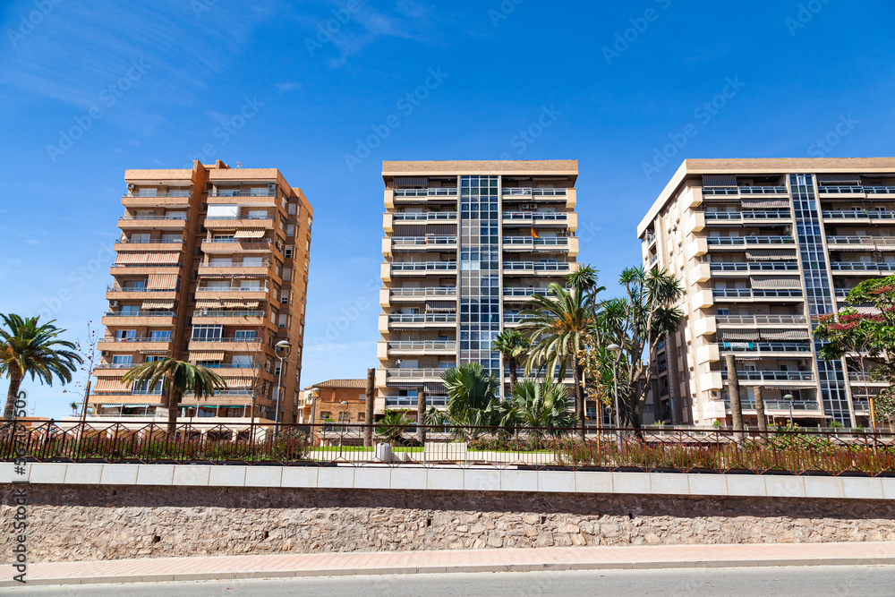 Property in Spain. Apartments in Spain and next to growing palm trees. Spanish high-rise residential buildings.