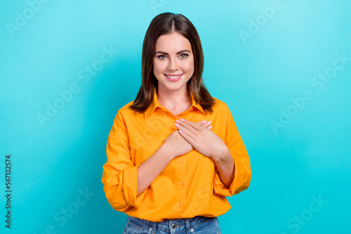 Photo of pretty charming lady wear orange shirt smiling hands arms heart isolated turquoise color background
