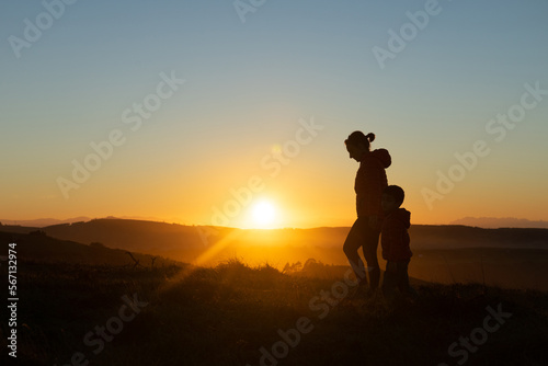Mother and son silhouetted at sunset when walking