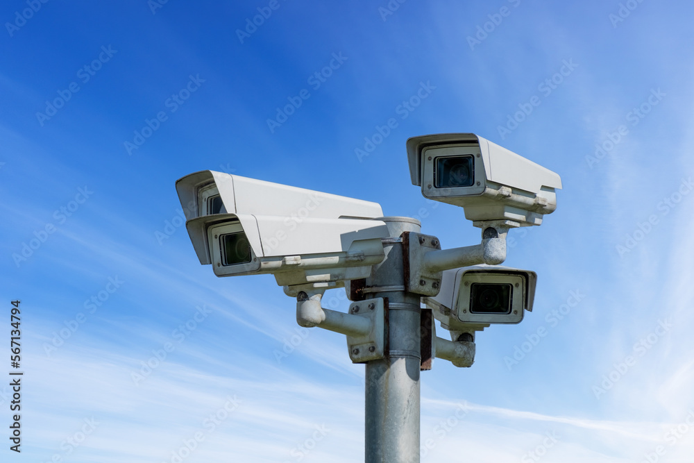 Four CCTV cameras on a pillar against the blue sky. Four CCTV cameras on a pillar against the blue sky.