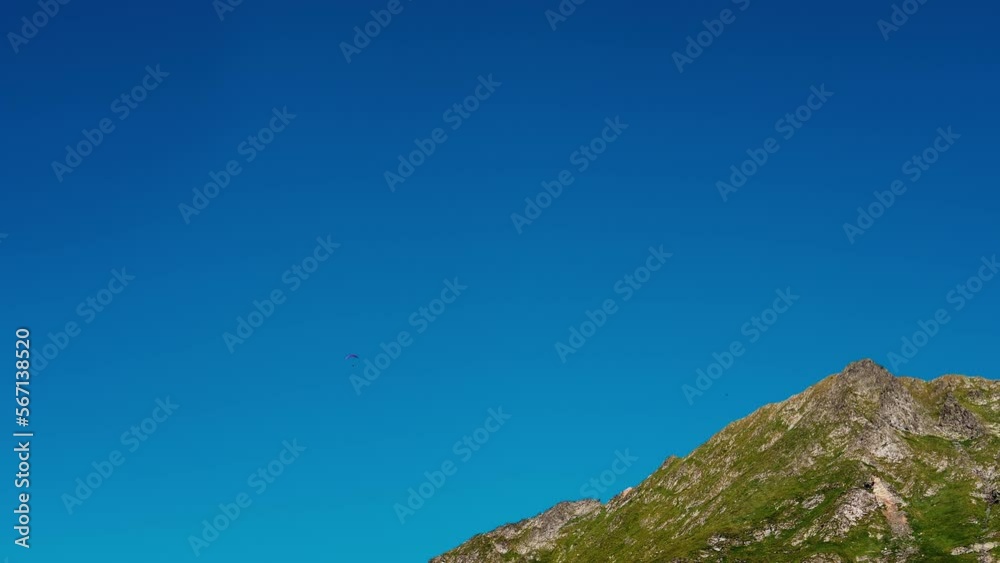 Parachutist in the distance over the mountain peak. Areal extreme sports on a clear skyduring a windy weather. Sport concept ideas. Parachutist in the distance over the mountain peak. Areal extreme sports on a clear skyduring a windy weather. Sport concept ideas.
