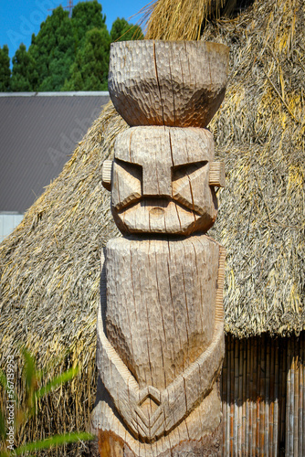 Figura mapuche tallada en madera al frente de una ruca photo