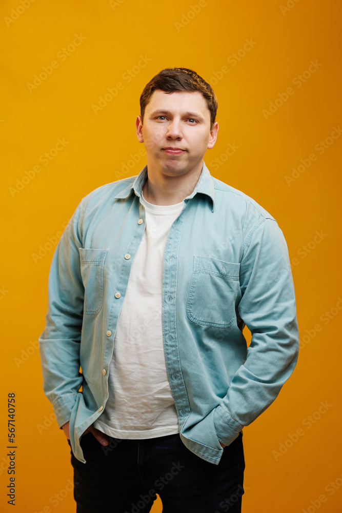 Fototapeta premium Portrait of handsome european man in shirt looking at camera standing on yellow studio background