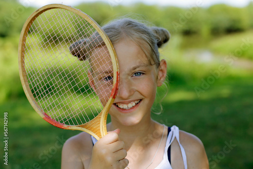 Blonde girl with a badminton racket on a green background. Active rest in summer. © Вера Шестопалова