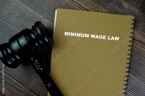 Concept of Minimum Wage Law write on a book with gavel isolated on Wooden Table.